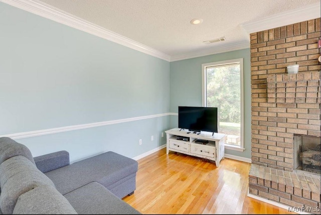 living room featuring a fireplace, ornamental molding, a textured ceiling, and light hardwood / wood-style flooring