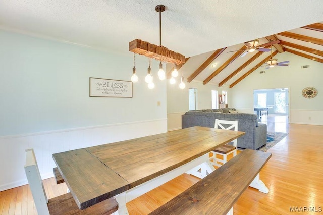 dining area featuring light wood-type flooring, a textured ceiling, lofted ceiling with beams, and ceiling fan