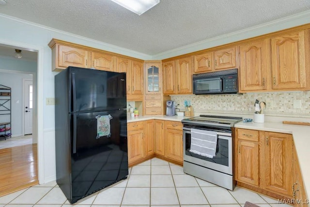 kitchen featuring light tile patterned flooring, a textured ceiling, ornamental molding, and black appliances