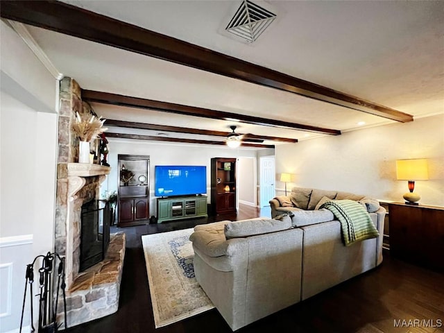 living room with dark hardwood / wood-style flooring, ceiling fan, crown molding, beamed ceiling, and a stone fireplace