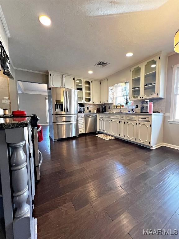 kitchen featuring decorative backsplash, ornamental molding, stainless steel appliances, and dark wood-type flooring