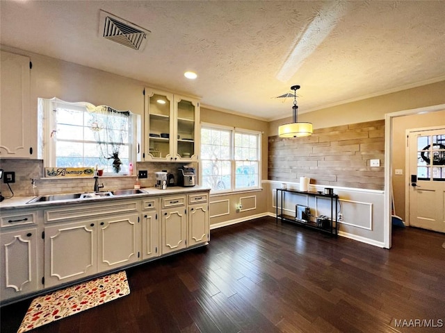 kitchen featuring sink, dark wood-type flooring, hanging light fixtures, a textured ceiling, and white cabinets