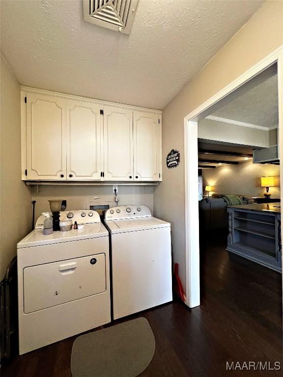 washroom featuring washing machine and clothes dryer, dark hardwood / wood-style floors, cabinets, and a textured ceiling