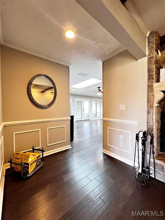 corridor with a textured ceiling, dark hardwood / wood-style floors, and ornamental molding