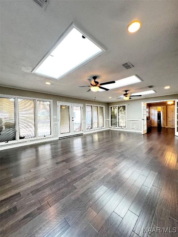 spare room featuring a textured ceiling, dark hardwood / wood-style flooring, a skylight, and ceiling fan