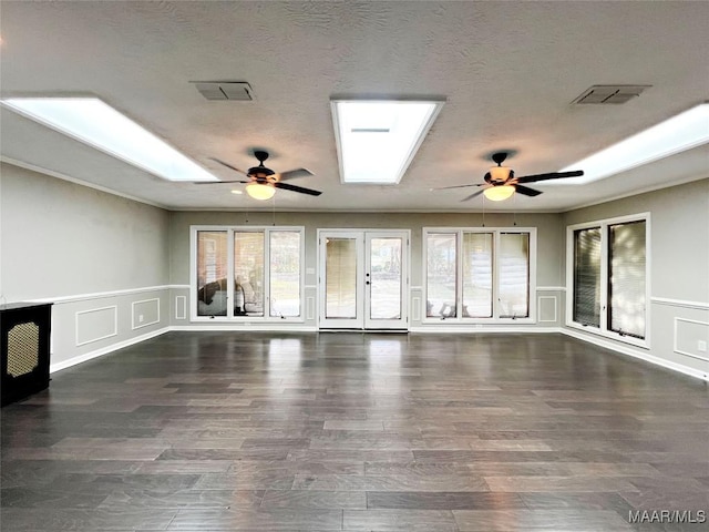 unfurnished living room with french doors, a skylight, ceiling fan, dark hardwood / wood-style floors, and a textured ceiling