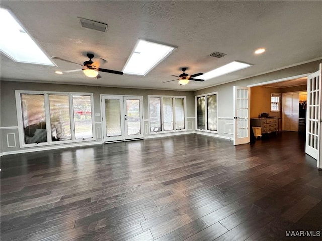 unfurnished living room featuring a skylight, ceiling fan, and french doors