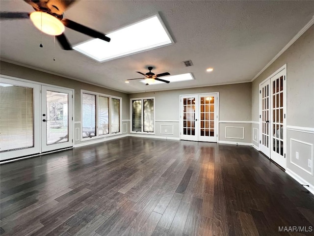 unfurnished living room with a textured ceiling, ceiling fan, dark wood-type flooring, and french doors