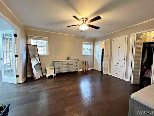 bedroom with ceiling fan, dark hardwood / wood-style flooring, ornamental molding, and two closets