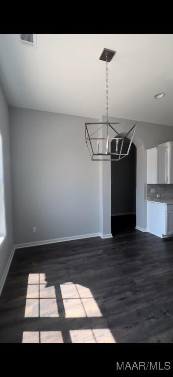 unfurnished dining area with dark hardwood / wood-style floors and an inviting chandelier