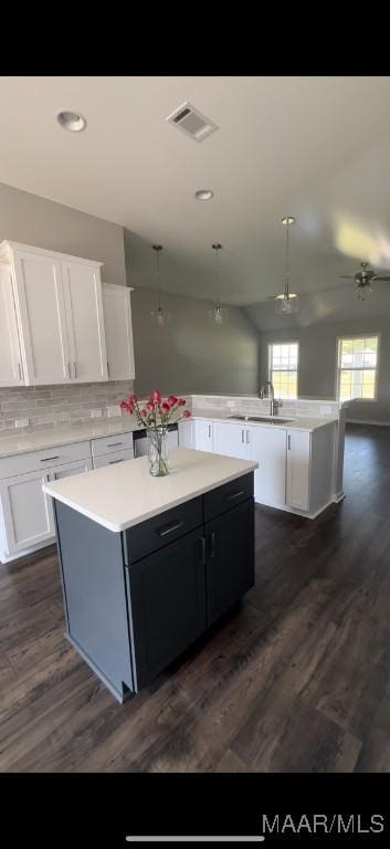 kitchen with kitchen peninsula, tasteful backsplash, a kitchen island, dark wood-type flooring, and white cabinetry