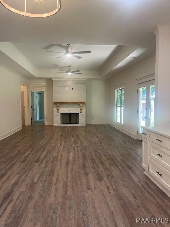 unfurnished living room with dark hardwood / wood-style floors, a raised ceiling, and ceiling fan