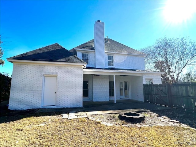 rear view of property featuring a fire pit, a patio area, and a lawn