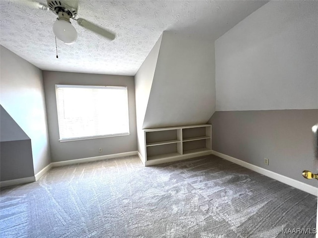 additional living space with carpet, a textured ceiling, vaulted ceiling, and ceiling fan