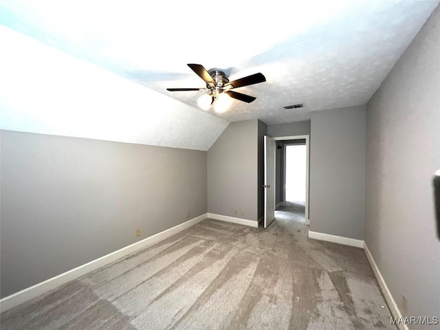 additional living space with a textured ceiling, ceiling fan, lofted ceiling, and light carpet