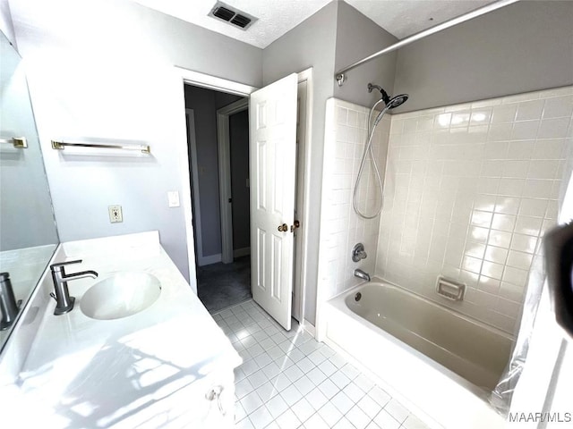 bathroom with tile patterned floors, vanity, and tiled shower / bath