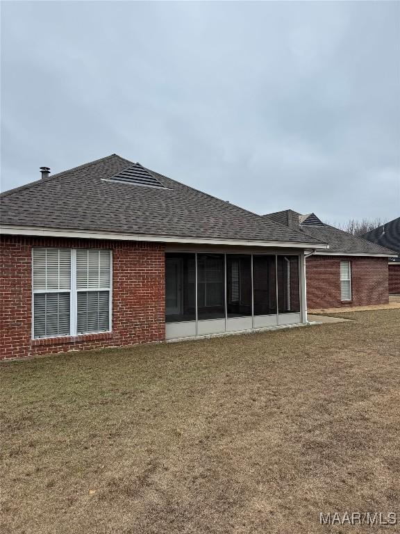 back of property with a sunroom and a lawn