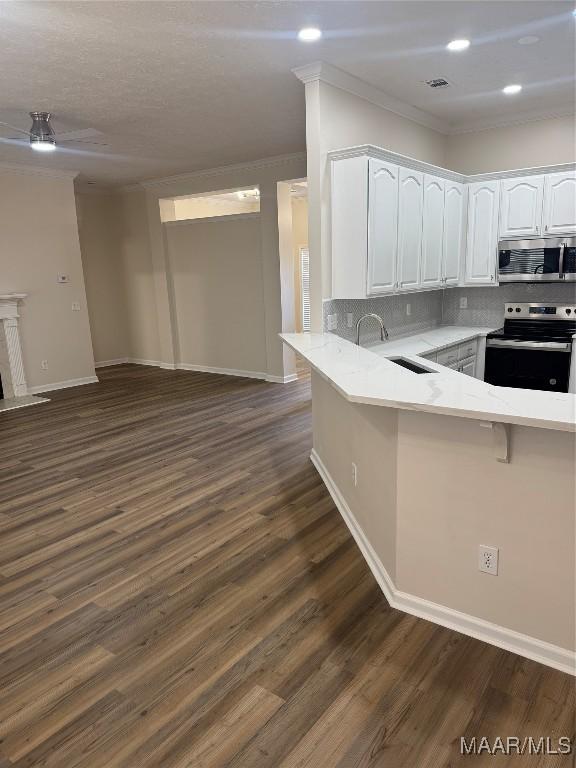 kitchen featuring kitchen peninsula, appliances with stainless steel finishes, dark hardwood / wood-style flooring, decorative backsplash, and white cabinets