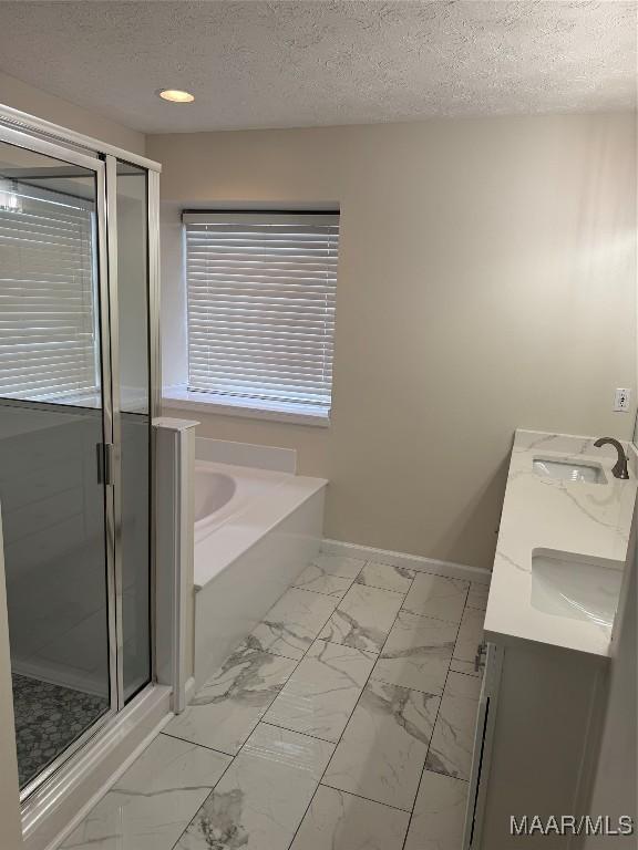 bathroom featuring separate shower and tub, vanity, and a textured ceiling