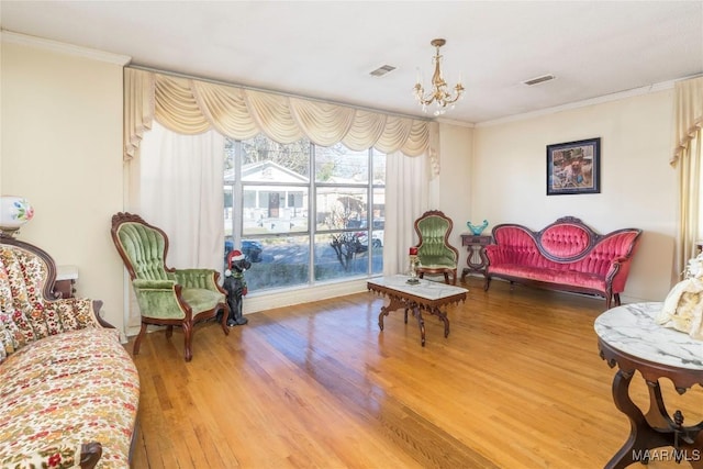 living area with wood-type flooring, crown molding, and a chandelier