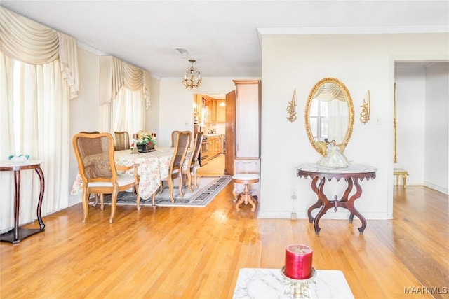 dining space with ornamental molding, a chandelier, and hardwood / wood-style flooring