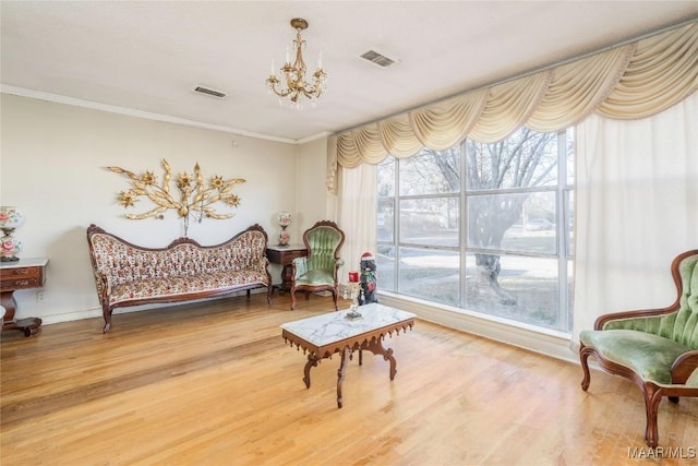 living area featuring a chandelier, hardwood / wood-style flooring, and ornamental molding