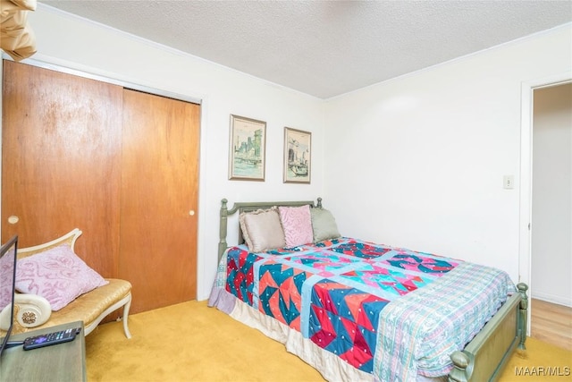 carpeted bedroom with a closet, a textured ceiling, and ornamental molding