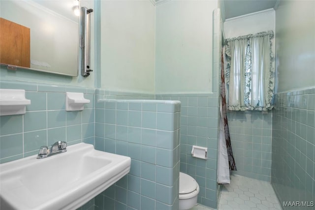 bathroom with toilet, tile walls, and sink