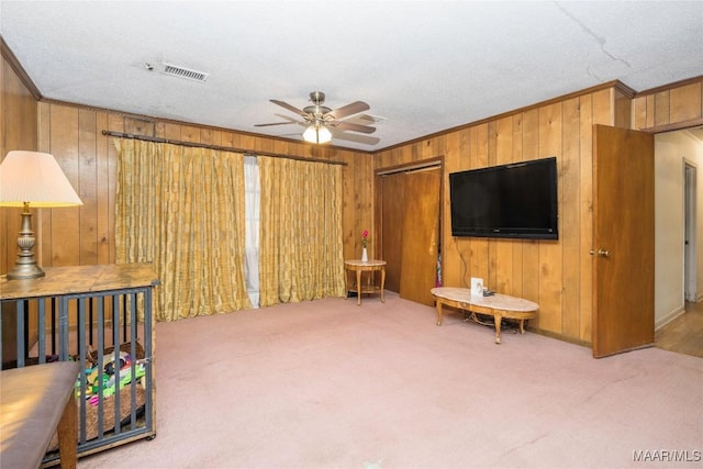 carpeted living room with ceiling fan, ornamental molding, and a textured ceiling