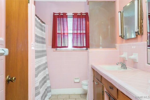 bathroom featuring tile patterned flooring, vanity, toilet, and tile walls