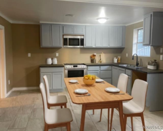 kitchen with gray cabinetry, sink, stainless steel appliances, light tile patterned floors, and ornamental molding