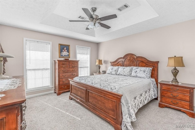 carpeted bedroom with ceiling fan, a textured ceiling, and a tray ceiling