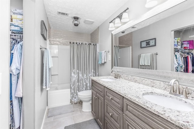 full bathroom featuring tile patterned flooring, a textured ceiling, toilet, vanity, and shower / tub combo