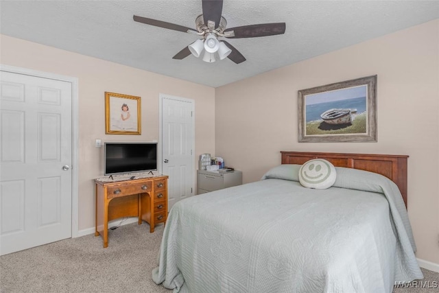 bedroom featuring ceiling fan, light carpet, and a textured ceiling