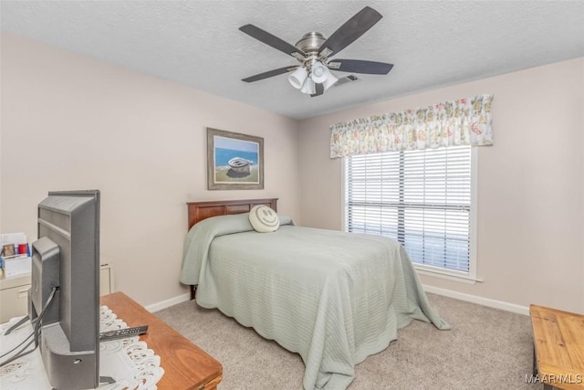 carpeted bedroom featuring ceiling fan and a textured ceiling