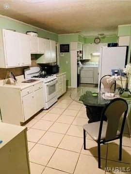 kitchen with white appliances, white cabinetry, and light tile patterned floors