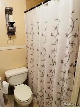 bathroom with a shower with shower curtain and toilet