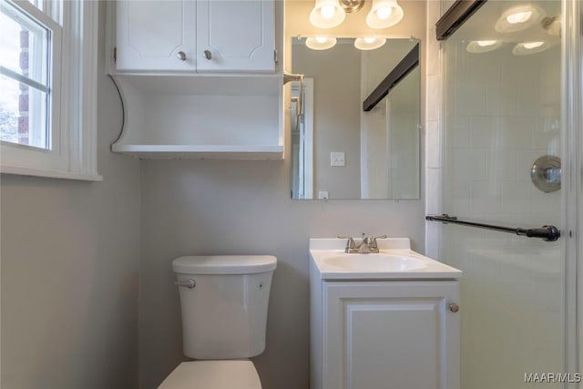 bathroom featuring vanity, toilet, and a shower with shower door