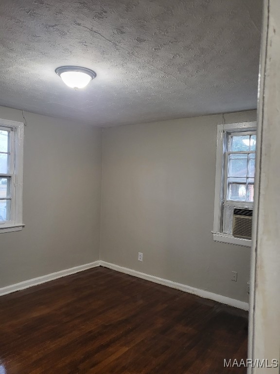 empty room with dark hardwood / wood-style flooring and a textured ceiling