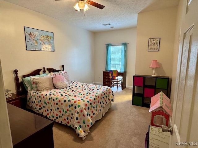 bedroom with ceiling fan, light colored carpet, and a textured ceiling