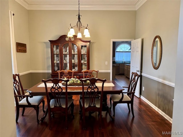 dining space featuring sink, dark wood-type flooring, a chandelier, and ornamental molding