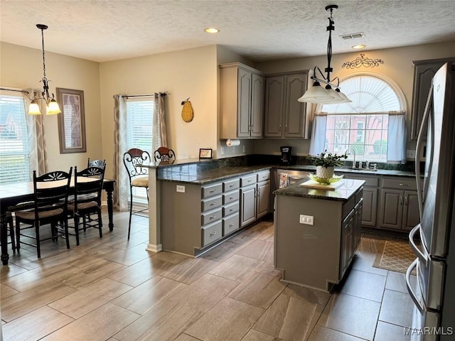 kitchen with gray cabinetry, a kitchen island, and decorative light fixtures