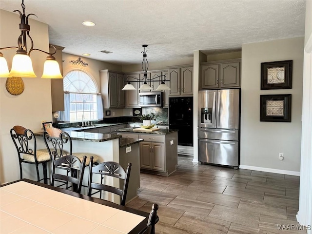 kitchen with gray cabinets, a kitchen island, decorative light fixtures, and appliances with stainless steel finishes