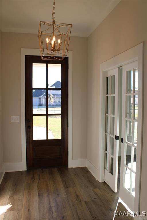 entryway with dark hardwood / wood-style floors, a chandelier, and french doors