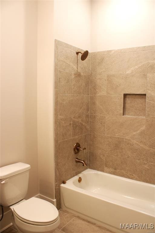 bathroom featuring tiled shower / bath, tile patterned floors, and toilet