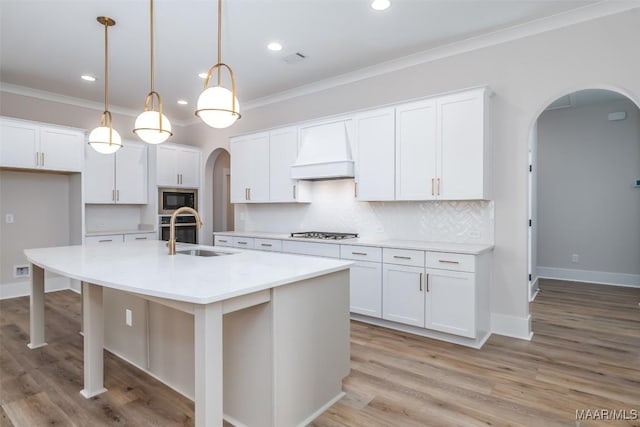 8325 Young Xing, Montgomery, AL 36116 - kitchen featuring arched walkways, custom range hood, black microwave, crown molding, and stainless steel gas cooktop
