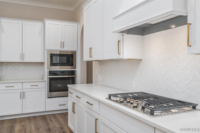8325 Young Xing, Montgomery, AL 36116 - kitchen with stainless steel appliances, custom exhaust hood, white cabinetry, backsplash, and ornamental molding