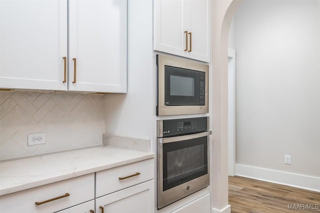8325 Young Xing, Montgomery, AL 36116 - kitchen with oven, black microwave, decorative backsplash, arched walkways, and white cabinets