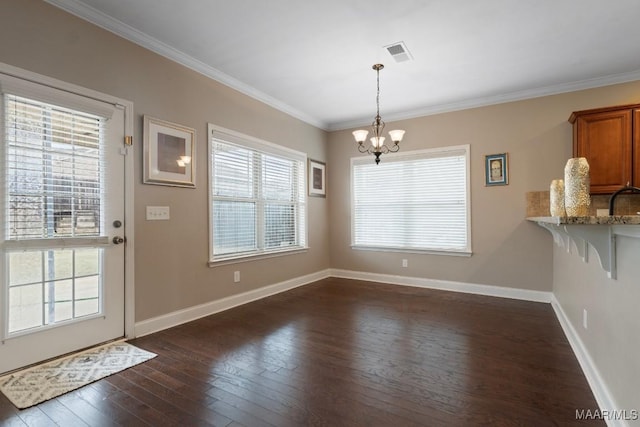 unfurnished dining area featuring ornamental molding, dark hardwood / wood-style flooring, a wealth of natural light, and a notable chandelier