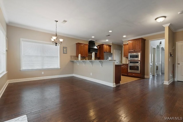 kitchen with hanging light fixtures, a kitchen bar, appliances with stainless steel finishes, custom exhaust hood, and ornamental molding